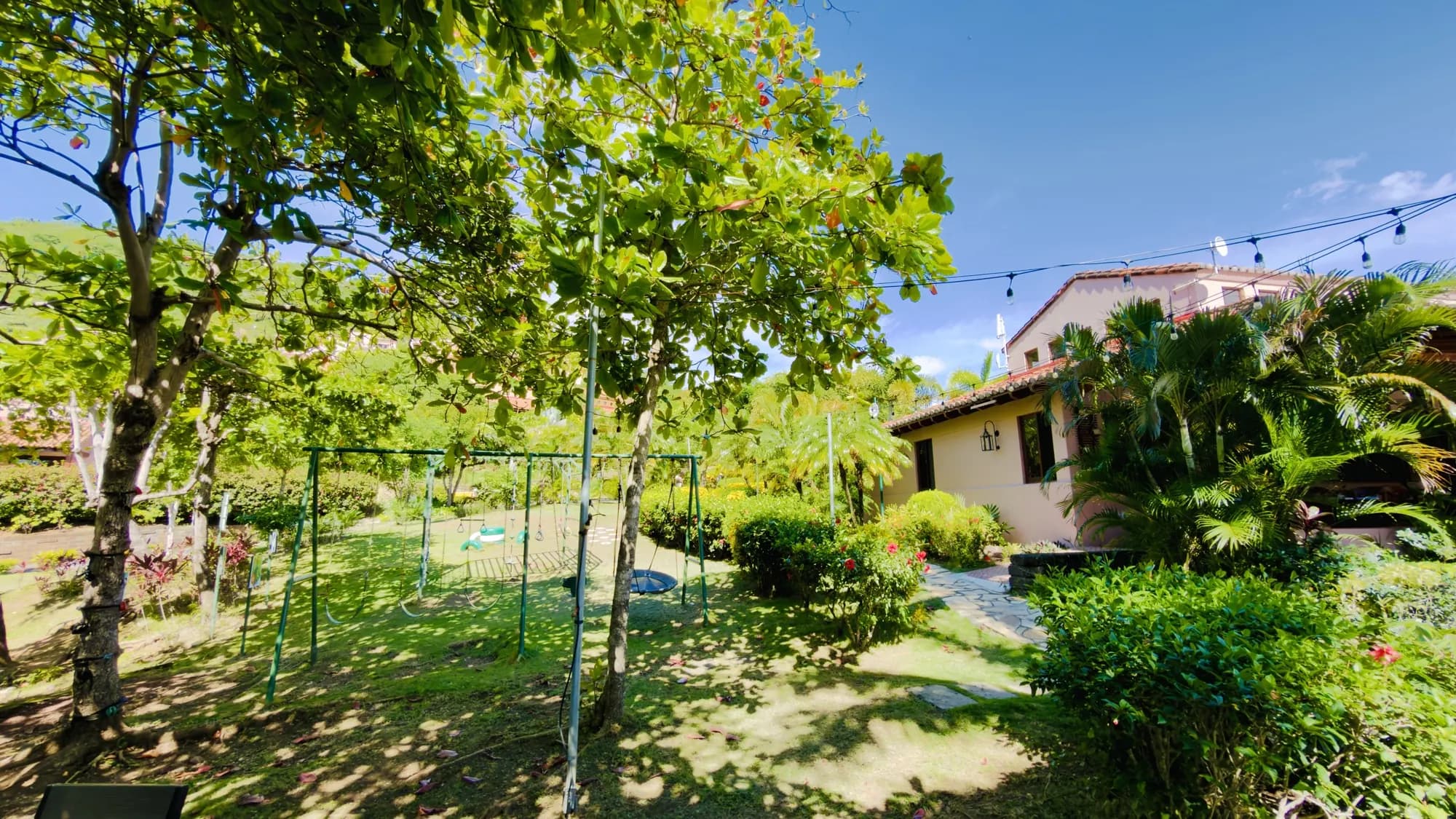 The gardens with the children's swings beside a villa