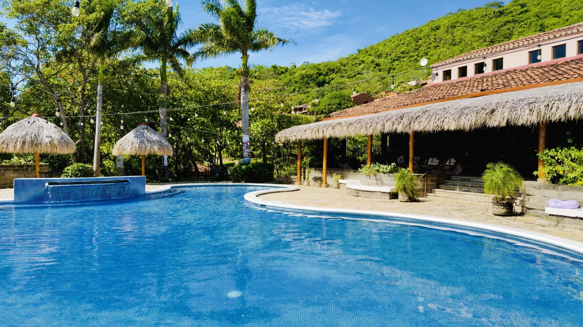 The pool with its palapas and the hillside villas behind