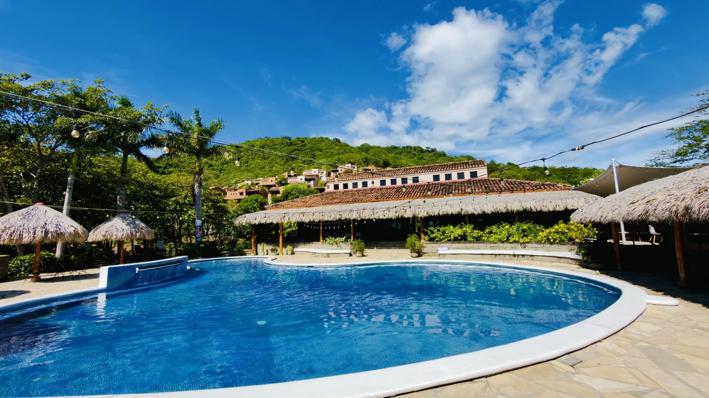 The pool with palapa umbrellas and the restaurant under its thatched roof