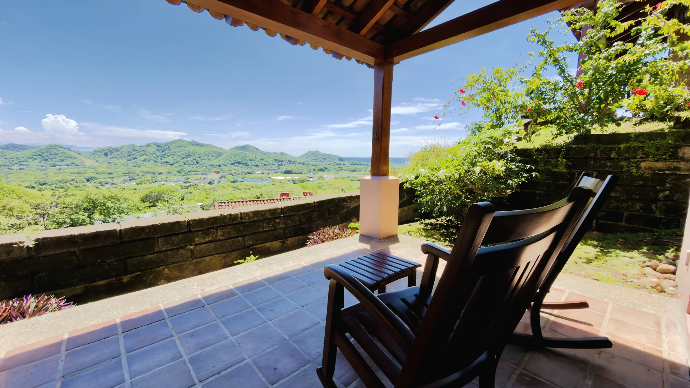 A rocking chair on a villa's covered terrace facing the hills and the ocean