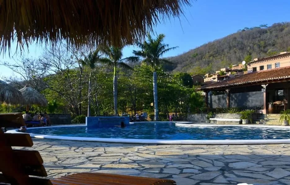 Camastros junto a la piscina con las colinas detrás
