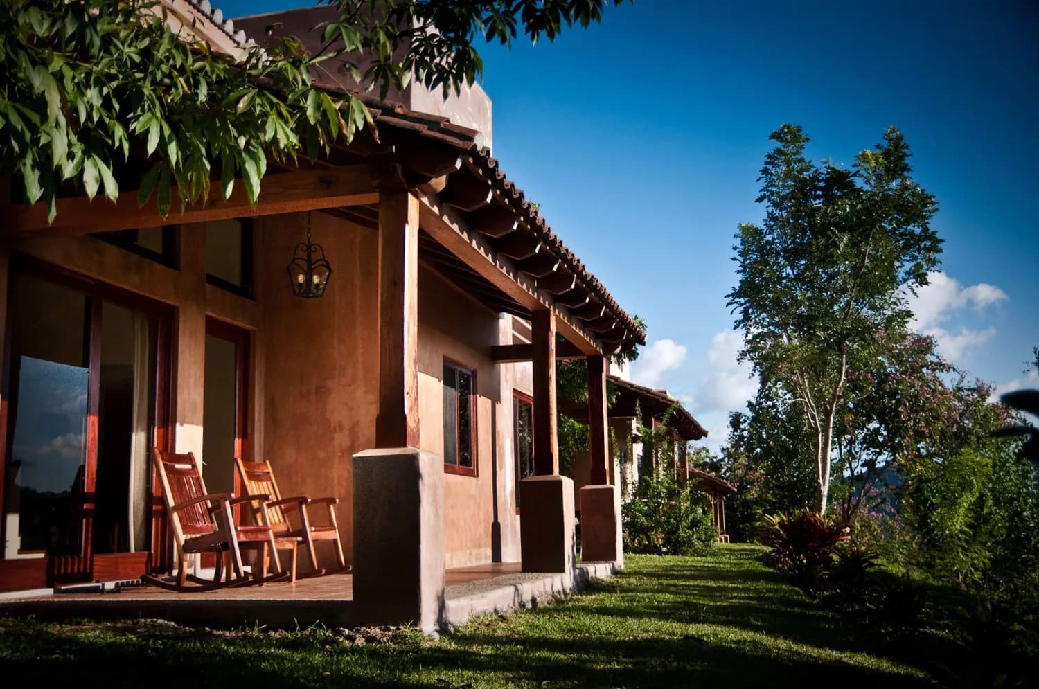 La terraza techada de una villa con mecedoras y las colinas detrás